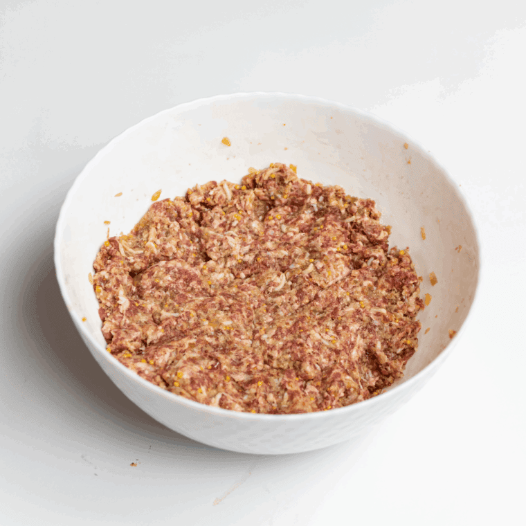 Combining meatloaf ingredients in a bowl, mixing until just combined to keep it tender.
