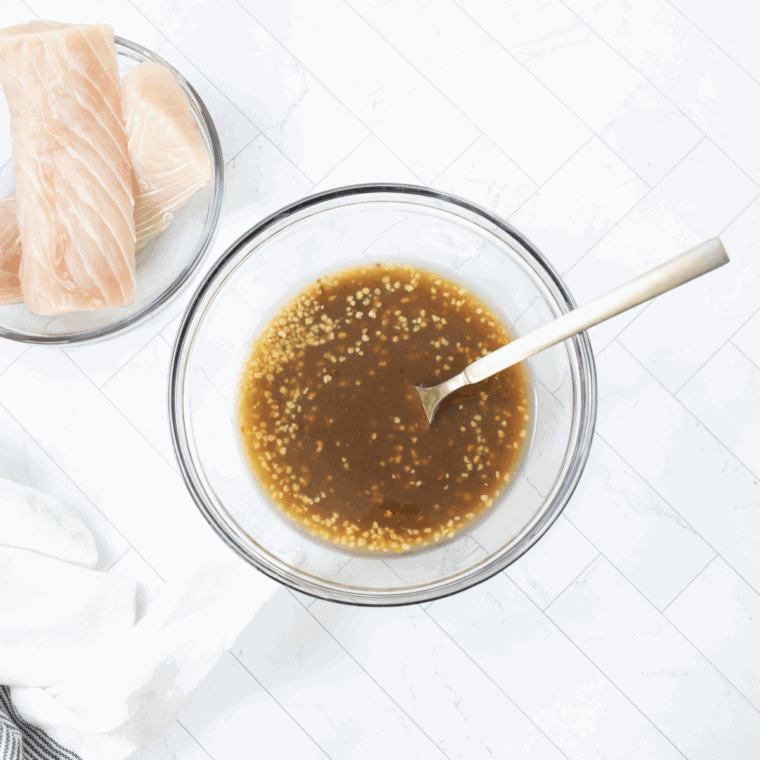 Mahi mahi fillets marinating in teriyaki sauce, sherry, and minced garlic in a shallow dish