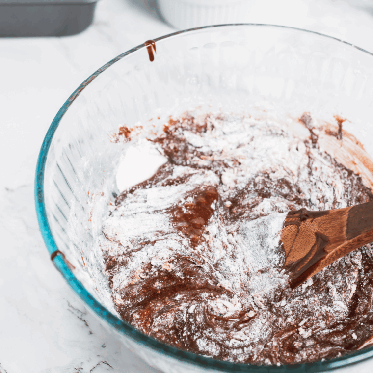 Mixing flour, cocoa powder, sugar, eggs, melted butter, vanilla extract, baking powder, and salt in a bowl.