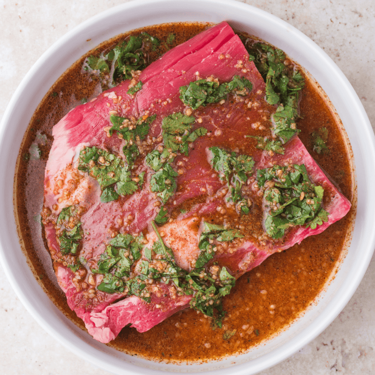 Mixing marinade ingredients in a bowl and coating steak for marination.