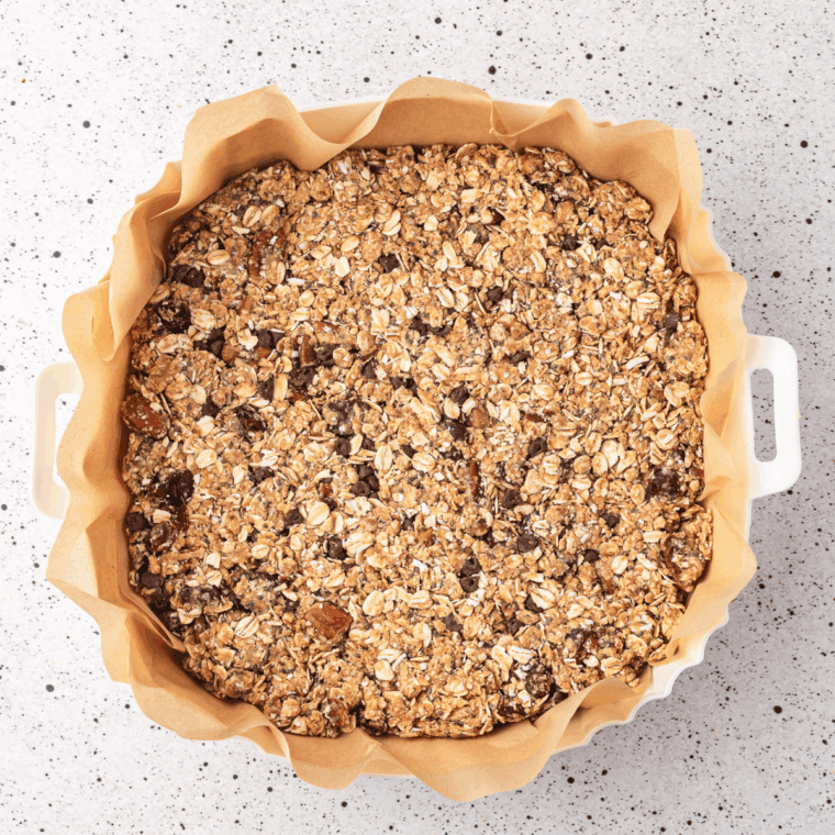 Low FODMAP granola spread in a single even layer on a parchment-lined baking sheet before baking