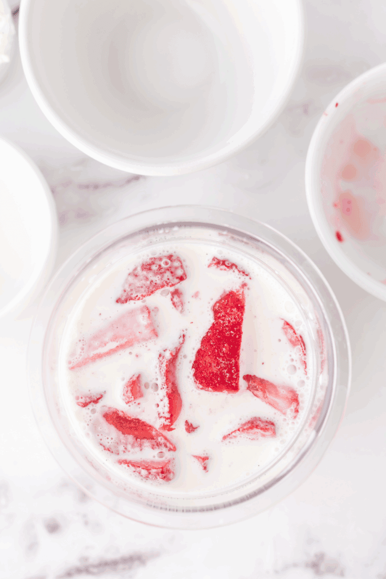 Blending fresh strawberries, cream cheese, milk, heavy cream, sugar, and vanilla extract.