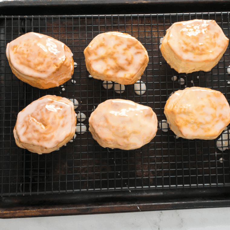 Dipping an air fryer maple bar into maple glaze and setting it on a rack