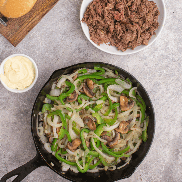 Cooked onions, mushrooms and green peppers in a skillet.