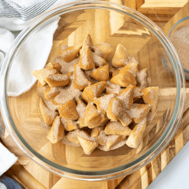 Coating biscuit pieces in cinnamon sugar and placing them in greased baking pan