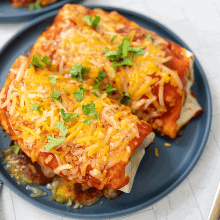Easy Blackstone griddle wet burrito covered in red sauce and melted cheese on flat top grill