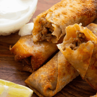 Golden, crispy homemade egg rolls filled with pork and vegetables, served with dipping sauce.