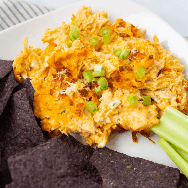 Cheesy Hooters Buffalo Chicken Dip in a cast iron skillet, topped with melted cheese and green onions, surrounded by tortilla chips