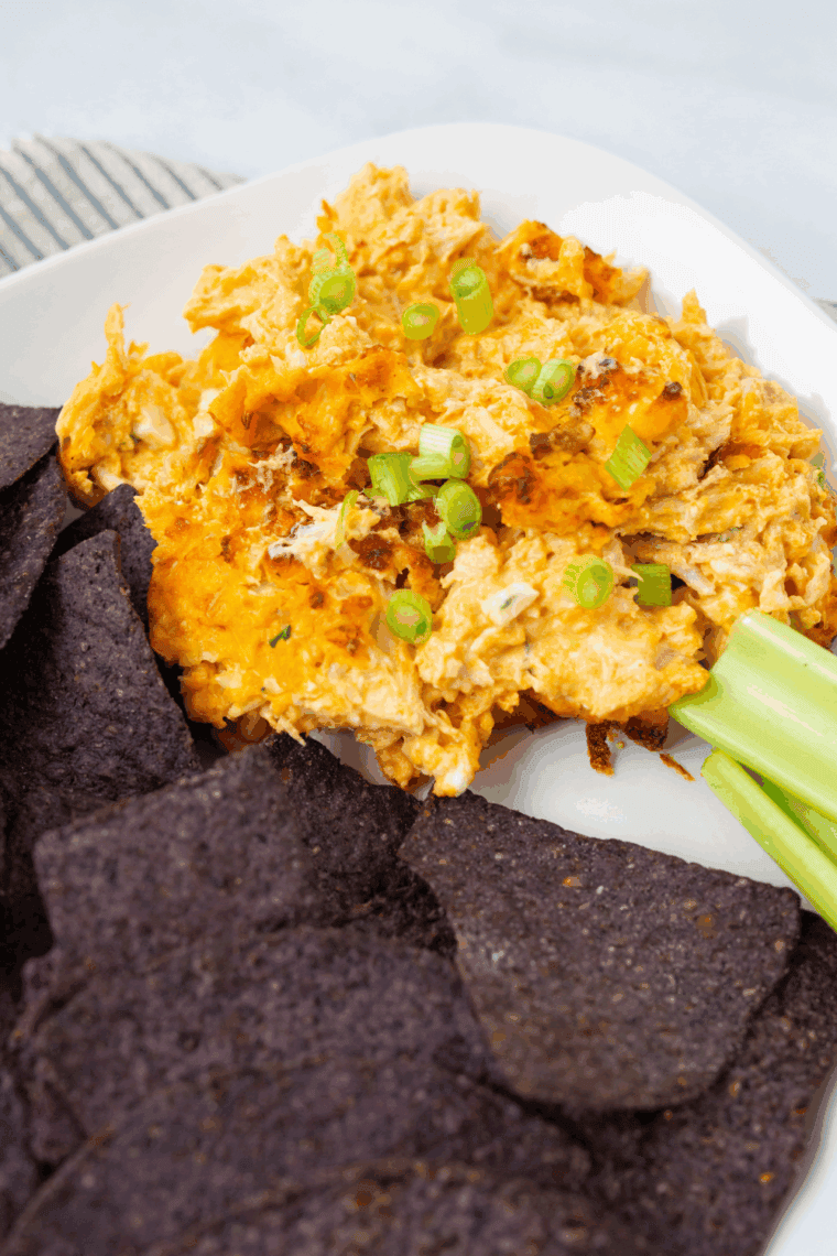 Hooters Buffalo Chicken Dip in a baking dish topped with green onions and served with tortilla chips — easy copycat appetizer recipe