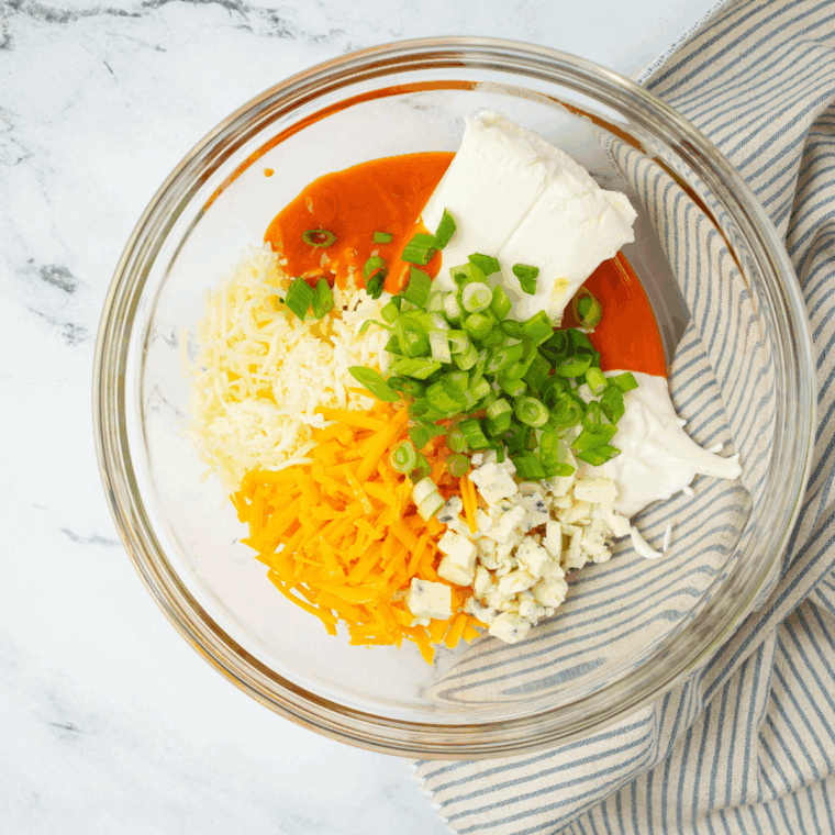 Shredded chicken, cream cheese, ranch, and buffalo wing sauce mixed together in a large bowl until smooth