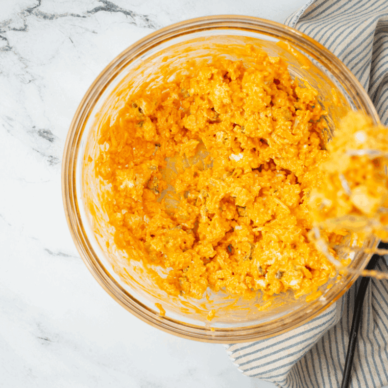 Folding shredded cheddar and mozzarella cheese into the creamy buffalo chicken mixture