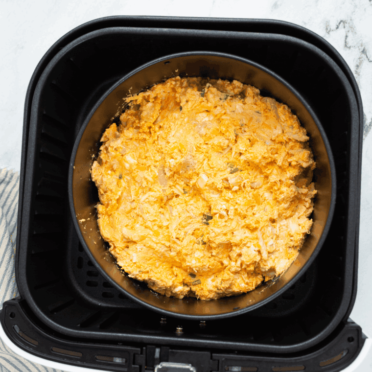Buffalo chicken dip spread evenly in a small air fryer-safe baking dish before cooking