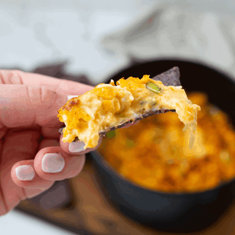 Creamy buffalo chicken dip served hot in a skillet, garnished with green onions and surrounded by chips for a game day snack