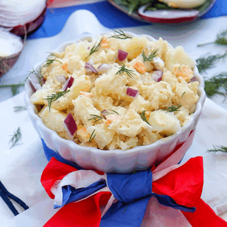 Vibrant Red, White, and Blue Potato Salad with creamy potatoes, fresh tomatoes, and blueberries, ideal for a festive summer meal or celebration.