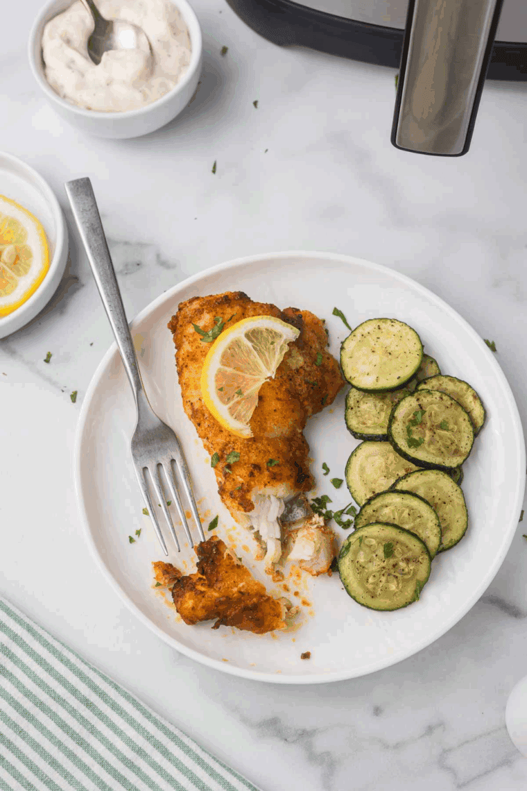 Golden-brown monkfish fillets cooked in the air fryer and served with lemon wedges and fresh herbs.
