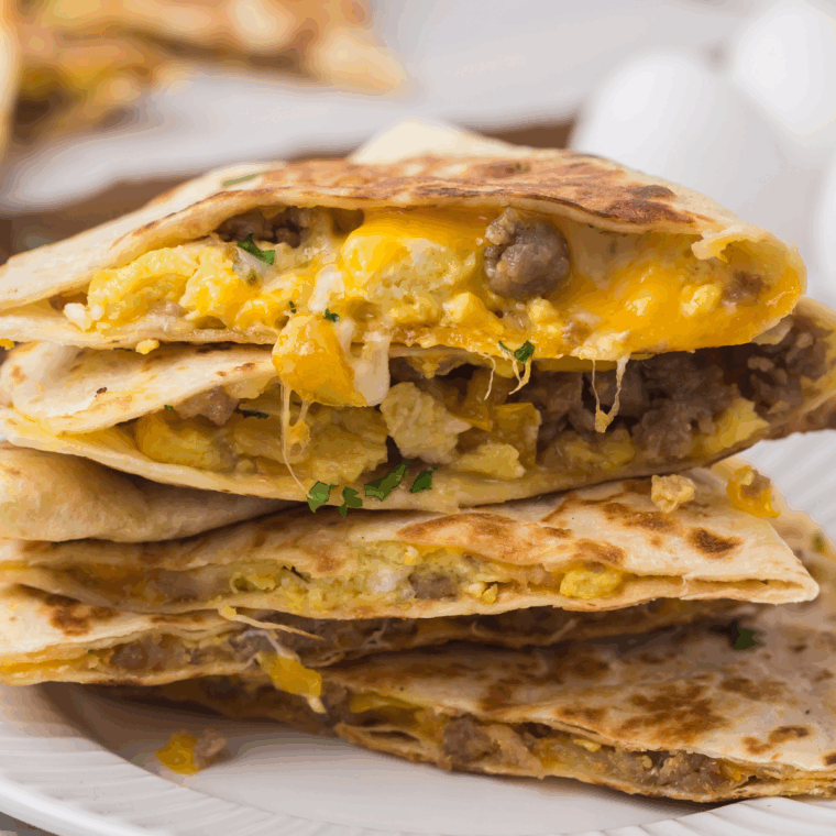 Easy Blackstone breakfast quesadillas filled with eggs, sausage, and melted cheese, sliced into wedges on a griddle