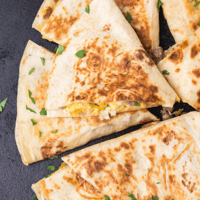 Sliced Blackstone breakfast quesadilla served with salsa and sour cream for dipping