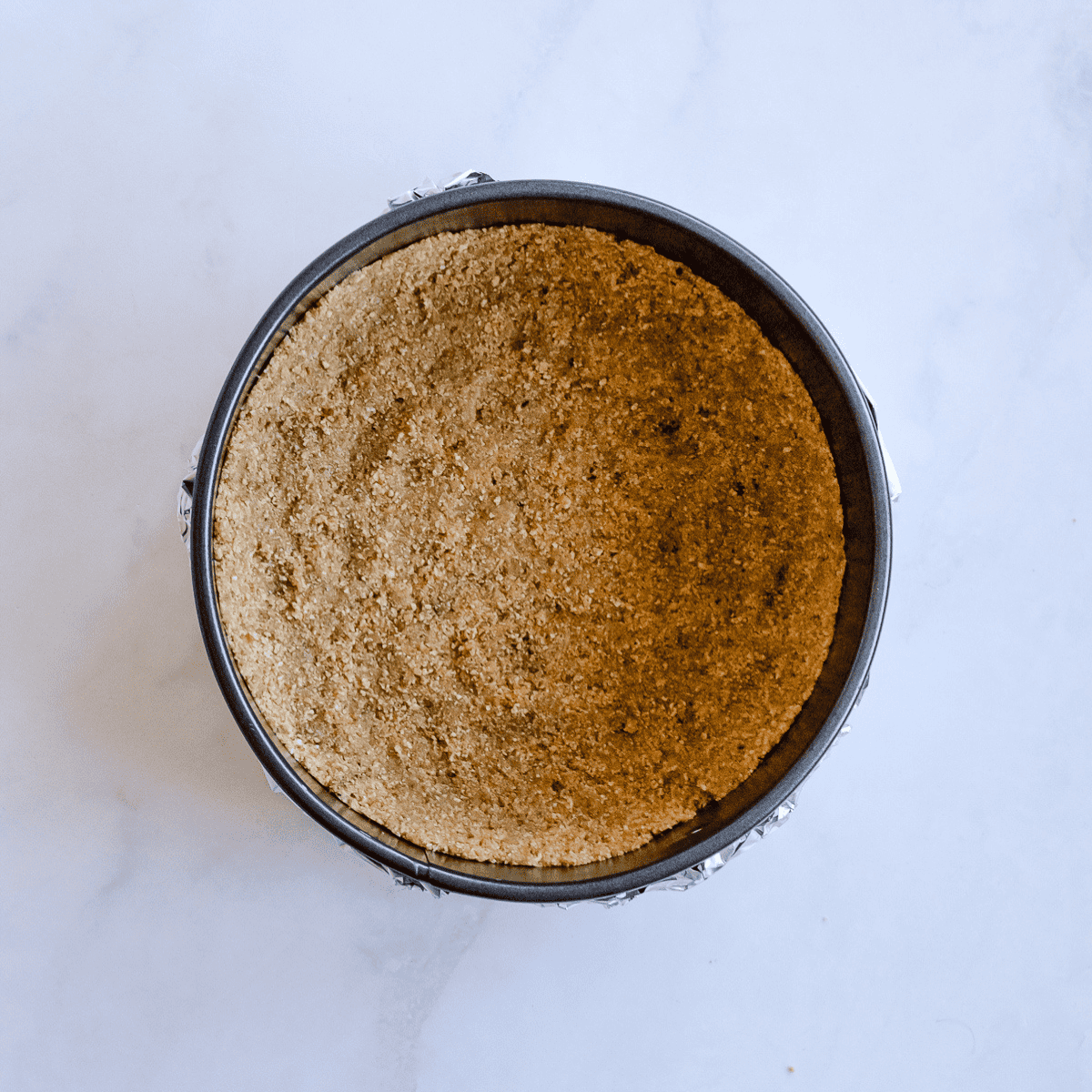 Pressing the graham cracker crust into a springform pan.