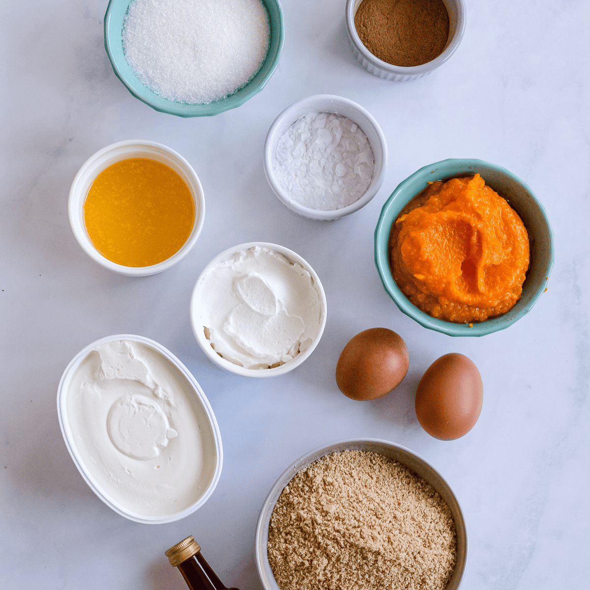Ingredients for pumpkin cheesecake: graham crackers, cream cheese, pumpkin purée, sugar, eggs, and spices.