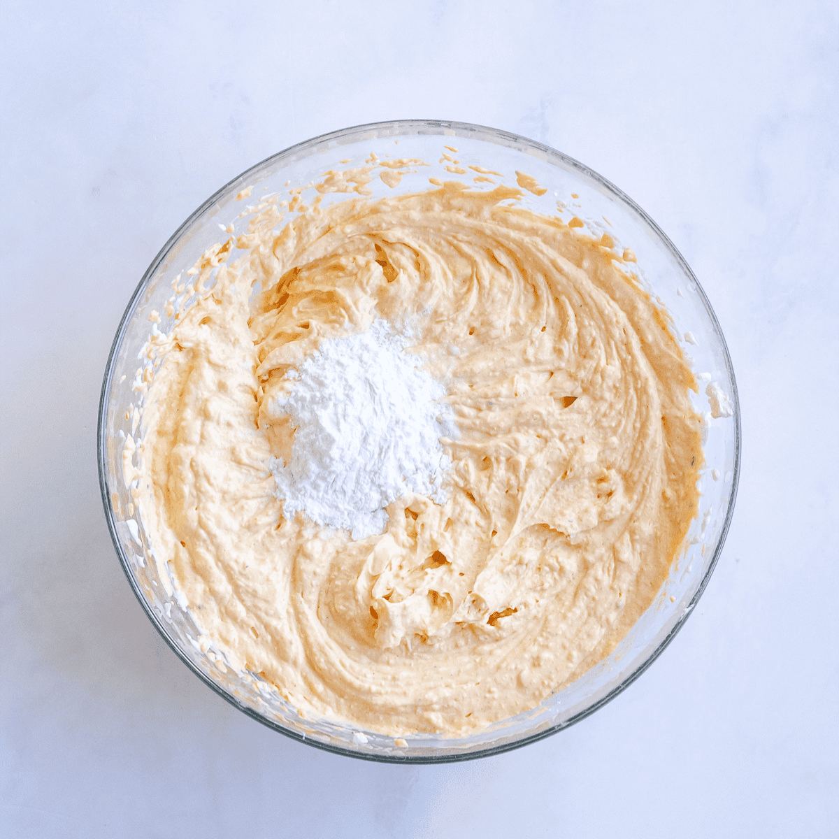 Pouring pumpkin cheesecake batter over the graham cracker crust.