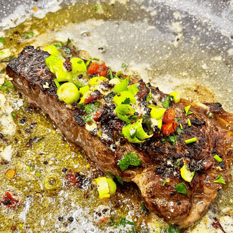 Cooked Cowboy Butter Steak  with fresh herbs and veggies.