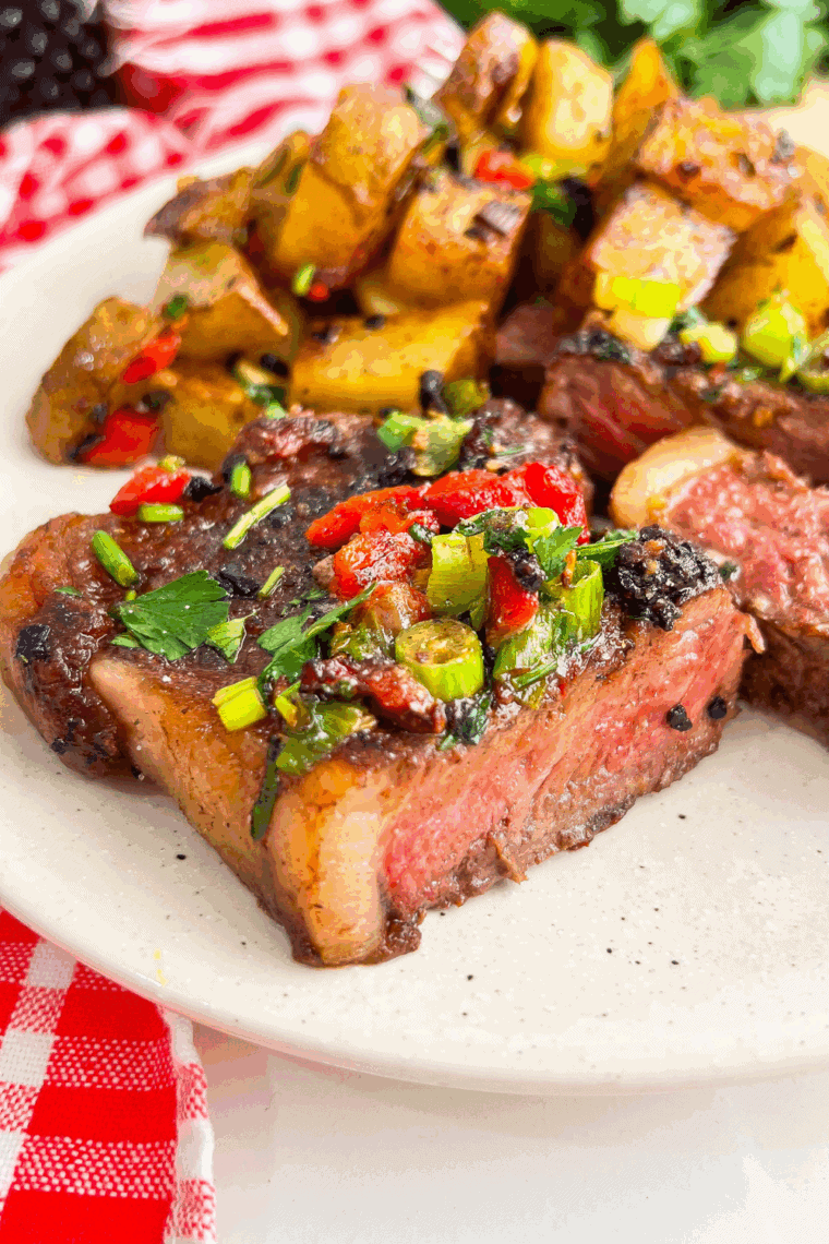 Skillet with juicy sliced steak and golden potatoes topped with cowboy butter sauce.

