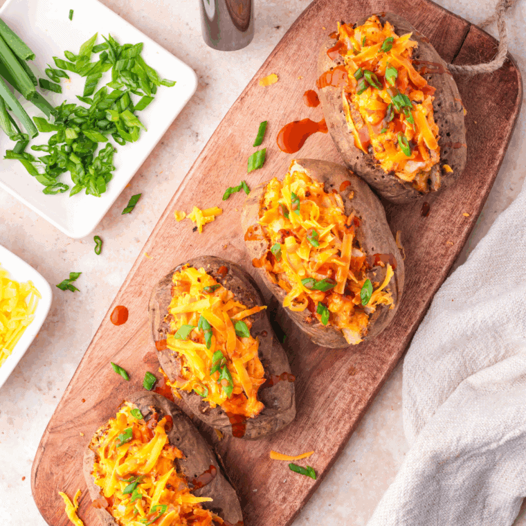 Mexican stuffed baked potatoes topped with cheese, beans, and fresh toppings on a plate.