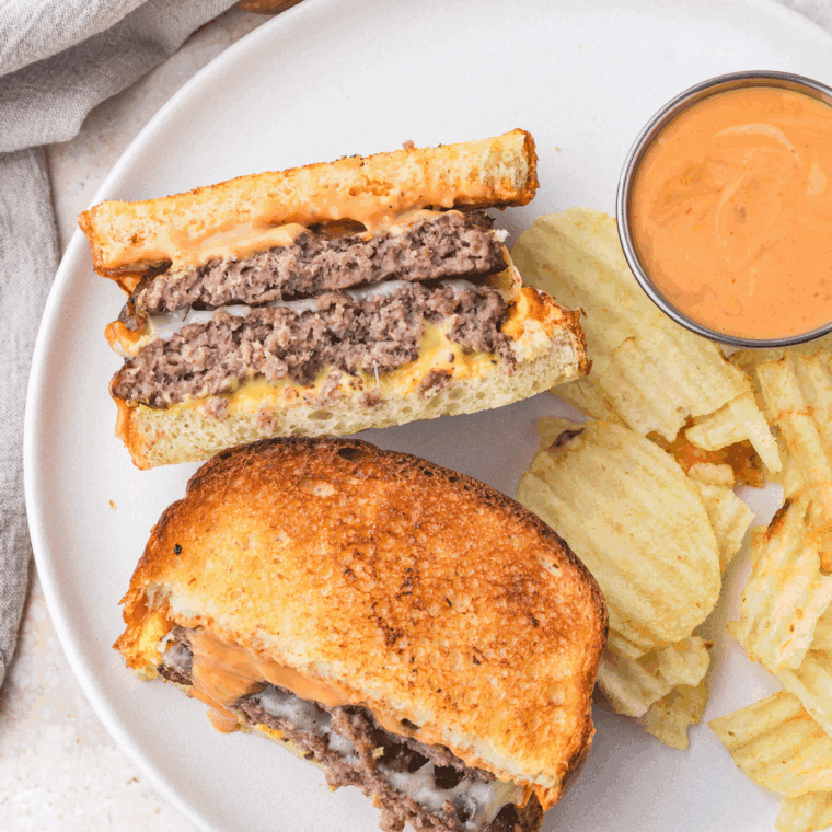 Cooked Hardee's Frisco Burger Recipe on plate with chips and sauce.