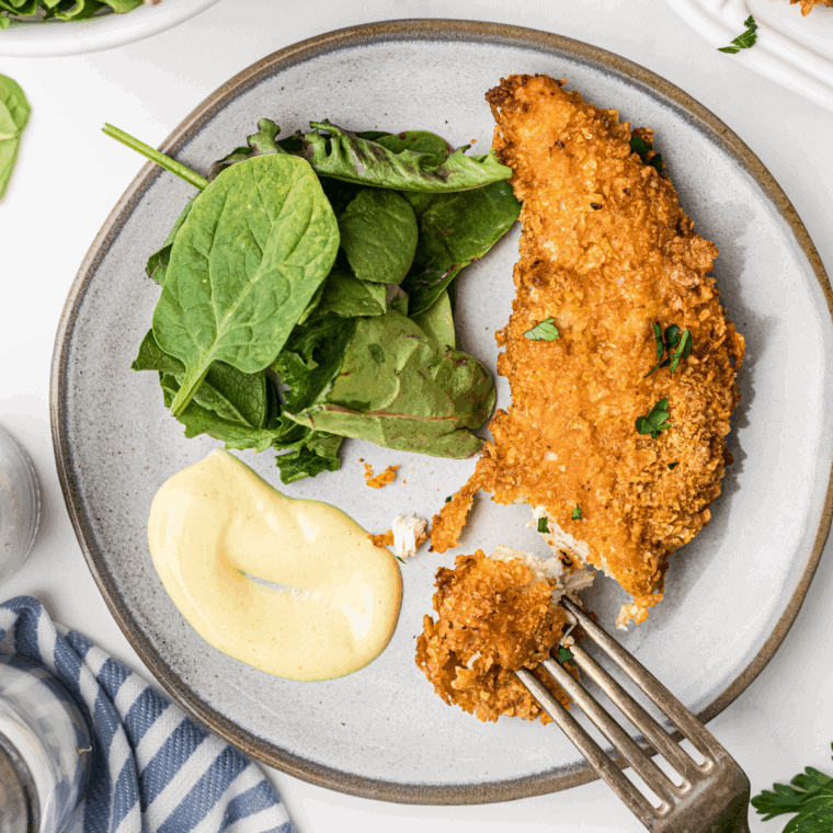 Bowl of homemade Hardee’s honey mustard sauce with a spoon and chicken tenders for dipping.