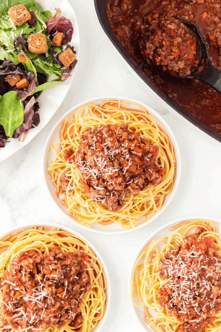 Rich Bolognese sauce cooking in the Ninja Foodi Possible Cooker Pro, topped with herbs and ready to serve over pasta.