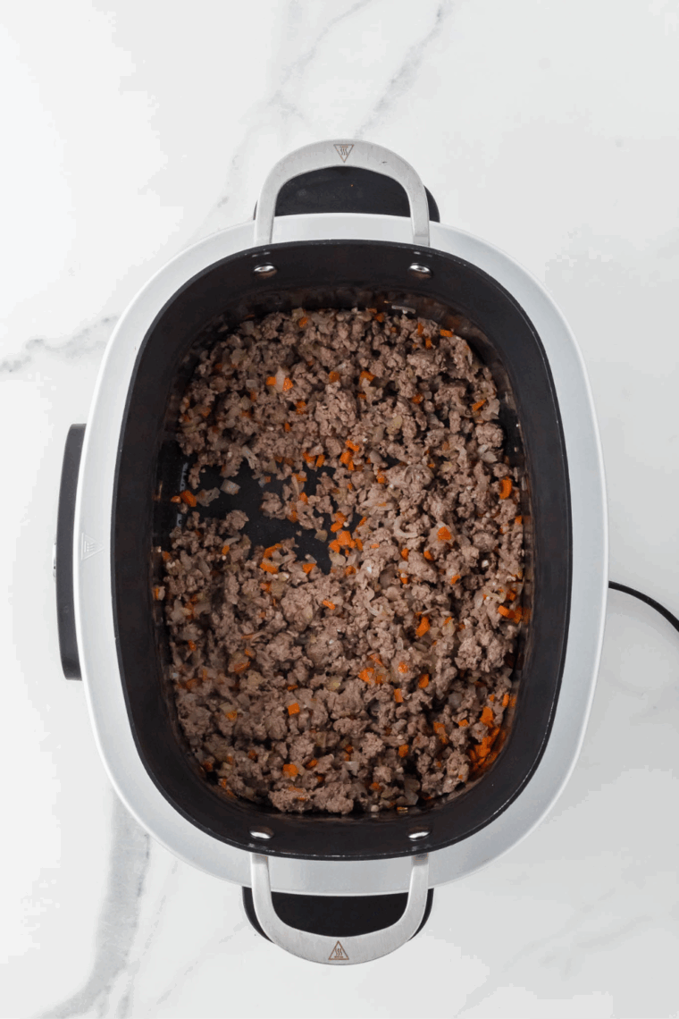 Browning ground beef in the Ninja Foodi, breaking it apart with a spoon.
