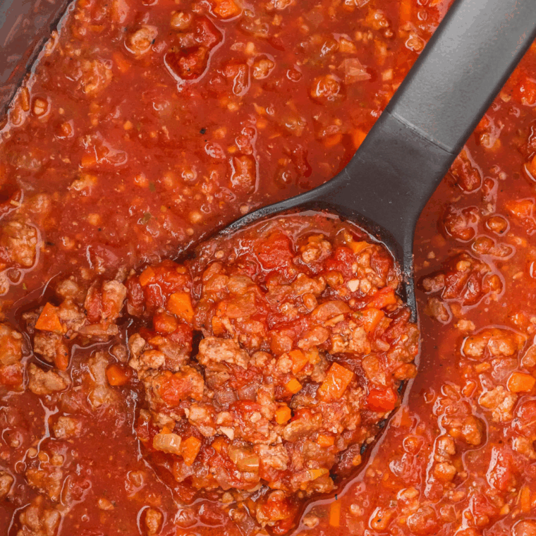 Serving rich Bolognese sauce over pasta, topped with grated Parmesan cheese.