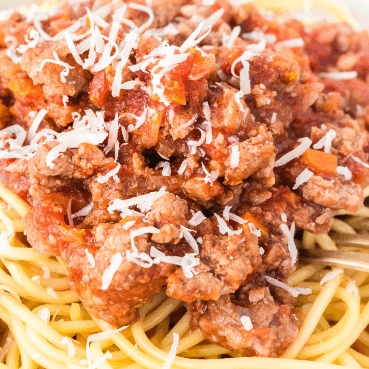 Hearty Bolognese sauce simmering in the Ninja Foodi Possible Cooker Pro, topped with herbs and served over a bed of pasta.