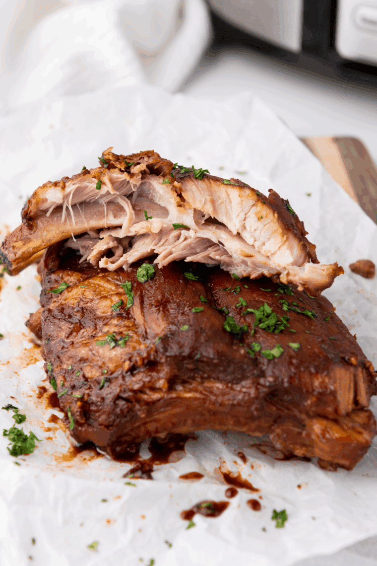 Finished slow cooker ribs coated in BBQ sauce, sliced and ready to serve