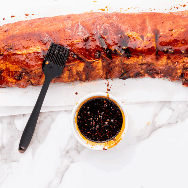 Rubbing a paprika and garlic powder spice blend onto raw baby back ribs