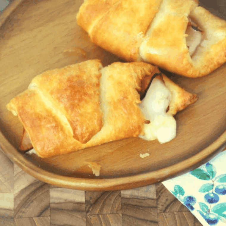 Golden air fryer ham and Swiss croissant roll-ups on a plate, served warm and melty.