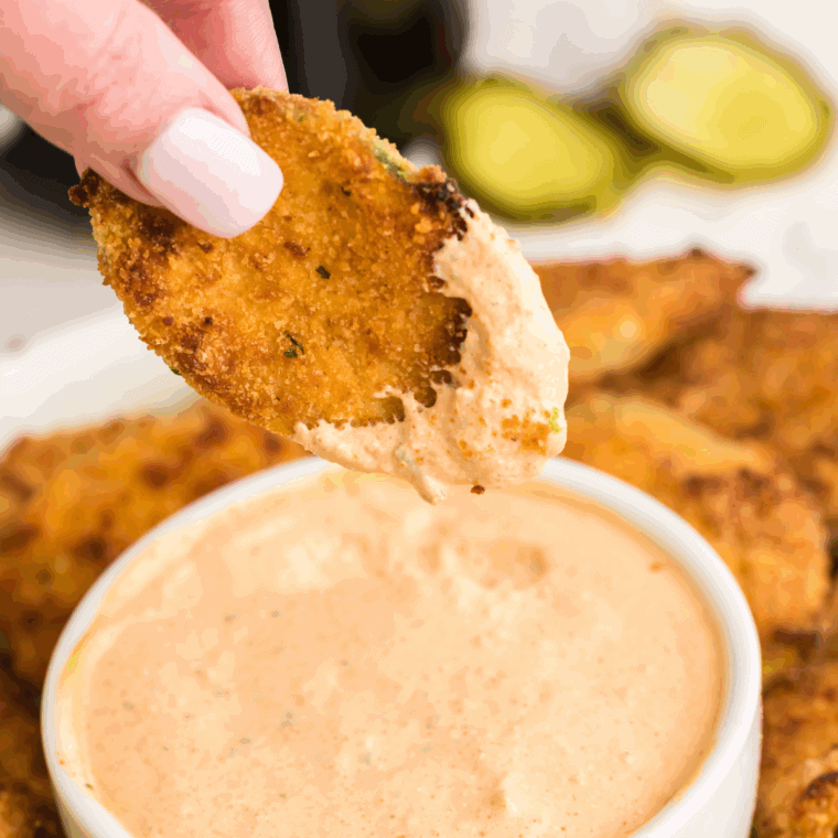 Golden, crispy Arthur Treacher’s fried pickles served with dipping sauce on a white plate.