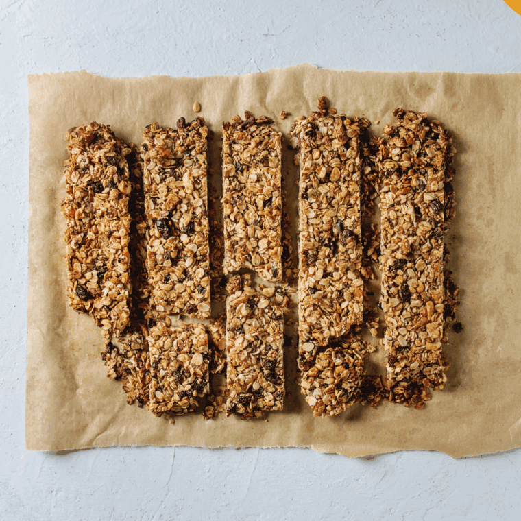 Homemade Copycat Quaker Chewy Chocolate Chip Granola Bars stacked on a plate with chocolate chips.