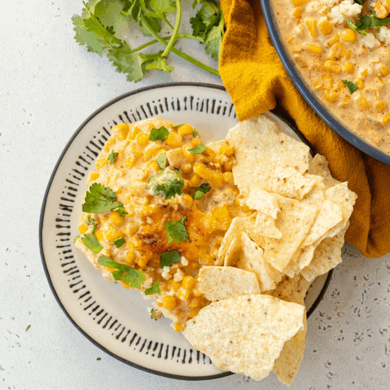 Easy Mexican street corn casserole topped with cotija, chili powder, lime, and cilantro in a white baking dish