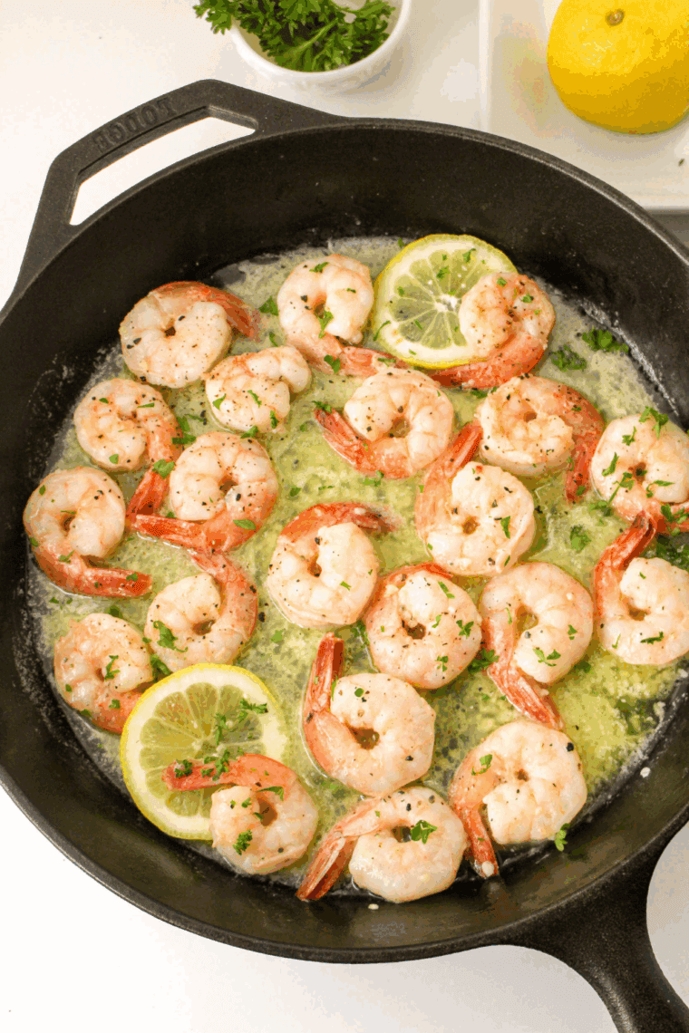 Minced garlic sizzling in skillet, with chicken broth and lemon juice added, simmering to reduce flavors.