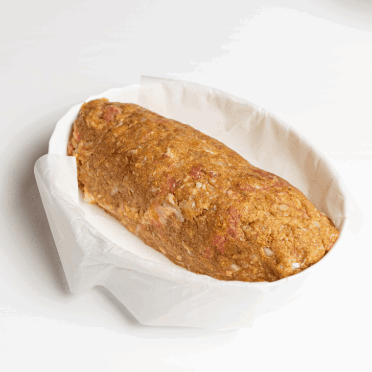 Shaped meatloaf placed in a baking dish with ketchup spread on top.