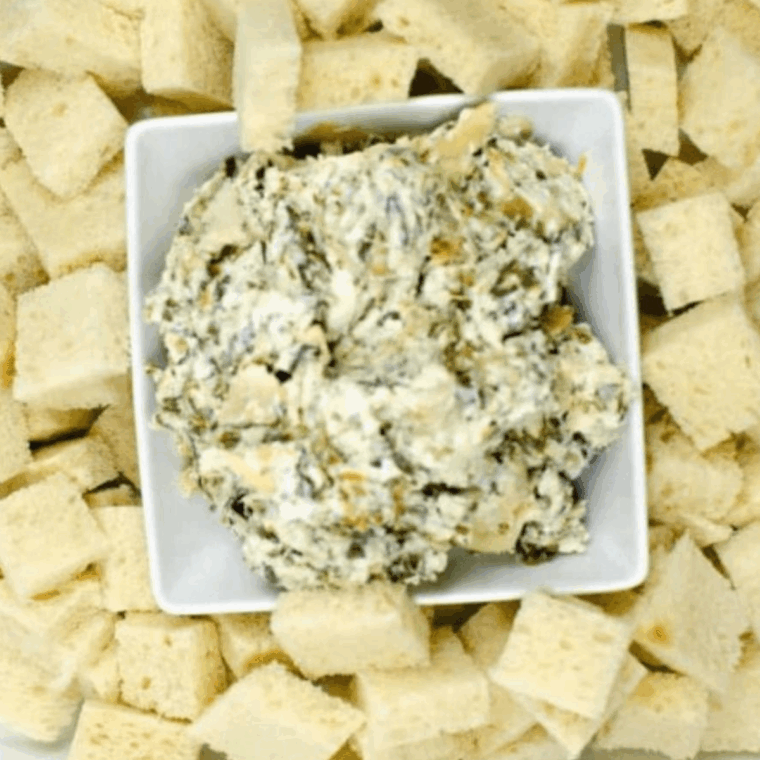 Creamy baked spinach artichoke dip served in a white dish, hot and bubbly.