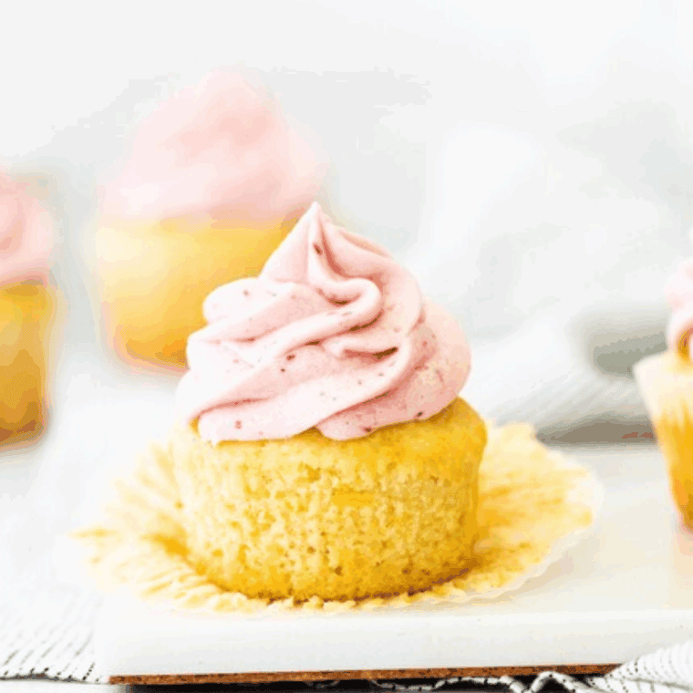 Freshly baked lemon raspberry cupcakes topped with creamy frosting and garnished with raspberries and lemon zest.