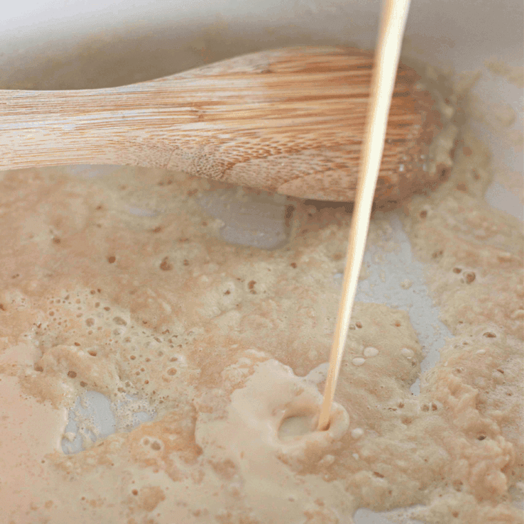 Melted butter and flour being whisked in a saucepan to form a smooth roux.