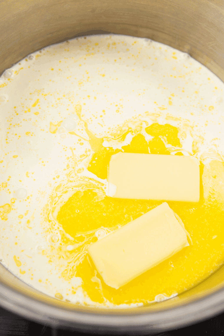 Cooking creamy Alfredo sauce in a skillet with butter, garlic, and heavy cream.