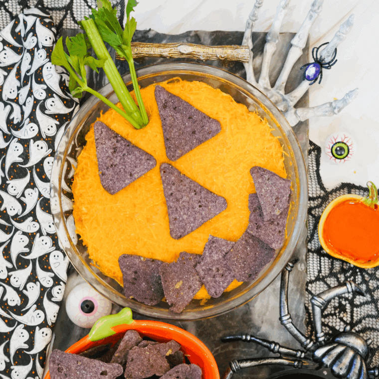 Halloween Boo-falo Wing Dip baked and decorated with tortilla chips and celery stem to resemble a pumpkin.