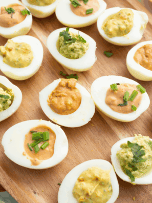 Homemade Ina Garten deviled eggs topped with paprika and fresh herbs, served on a platter for parties or holiday gatherings.
