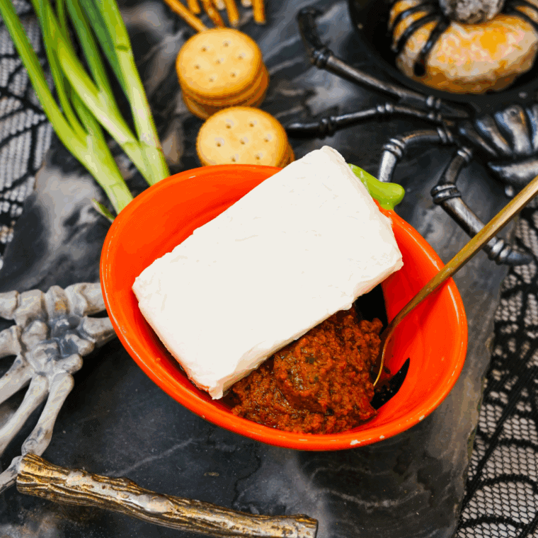 Mixing cream cheese with red Rosso pesto in a bowl.