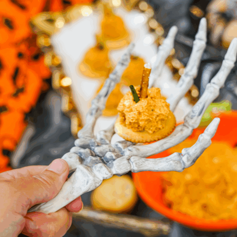 Mini pumpkin-shaped cheese balls on crackers, topped with pretzel stems and green onion, served as a festive fall appetizer.