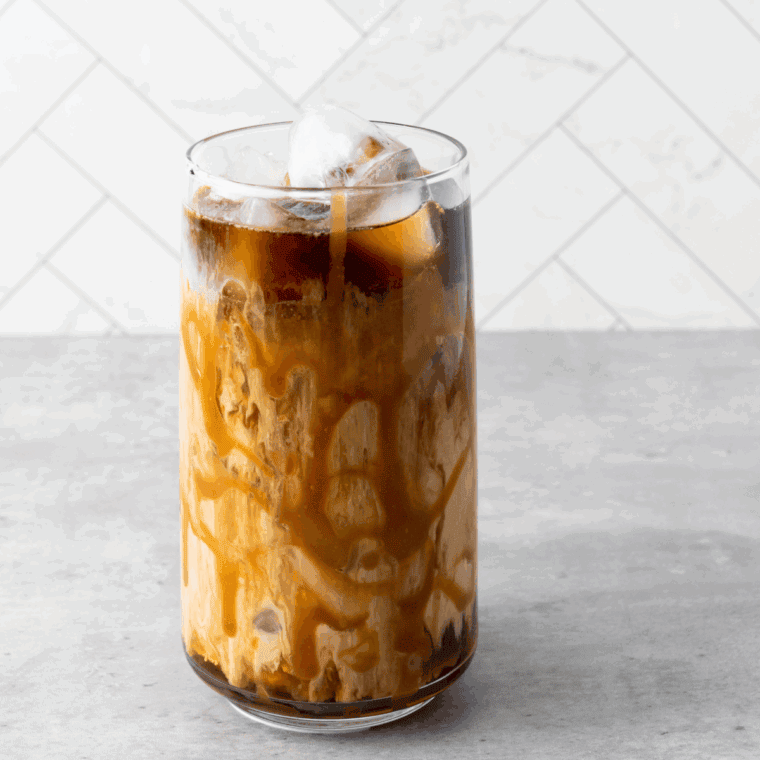 Glass of homemade Tim Hortons iced coffee with ice cubes, milk, and straw.